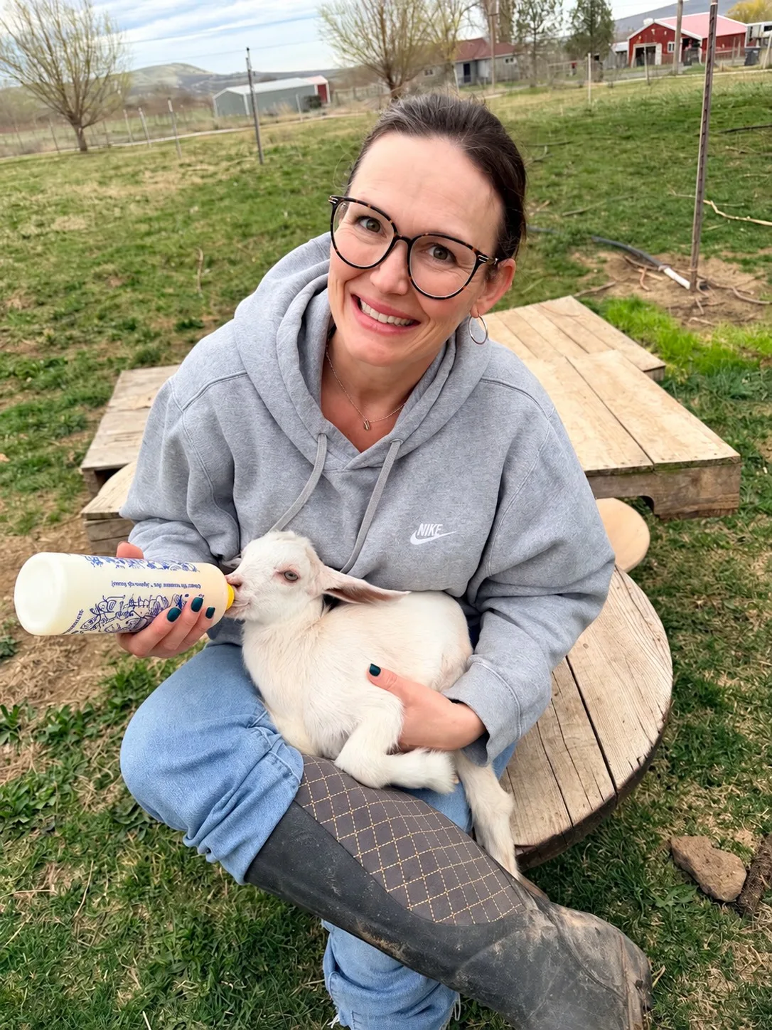 Rebecca Sullivan bottle feeding baby goat Dolly on her 5-acre homestead